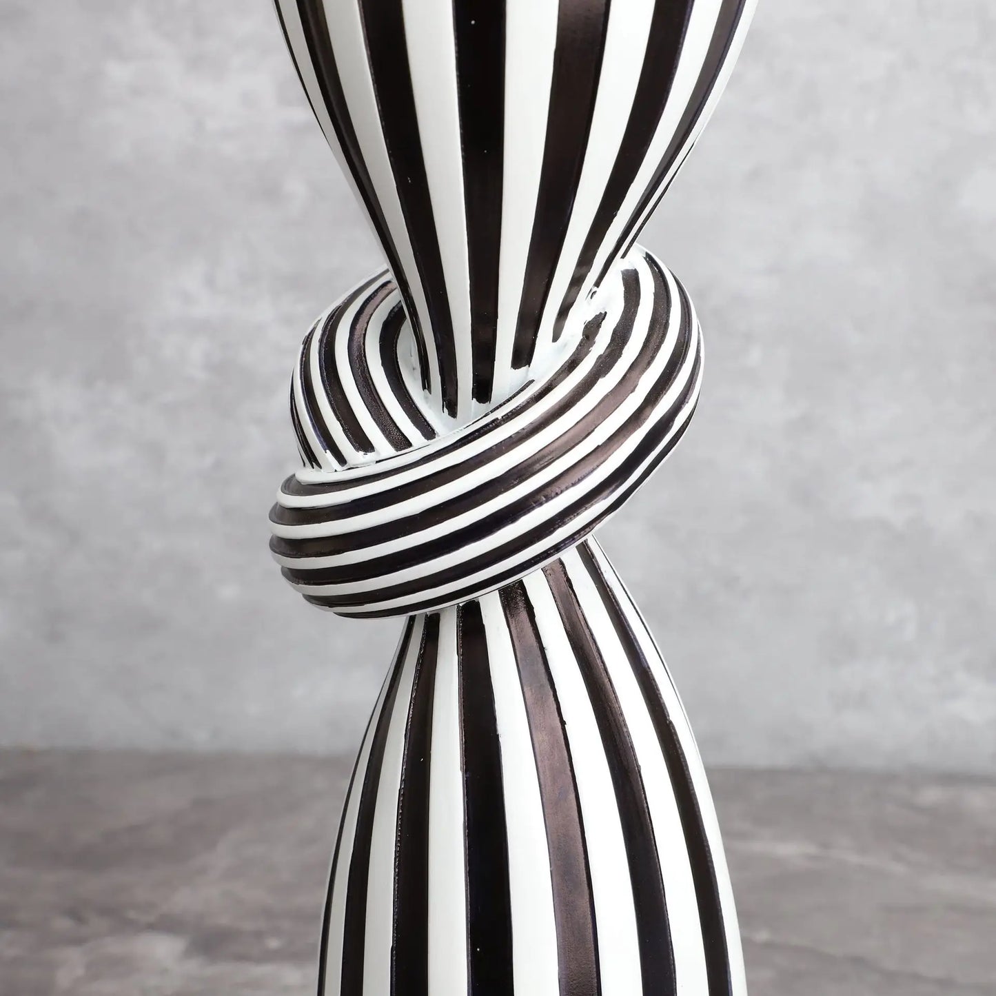 Black and white striped vase with a knot design on a gray background