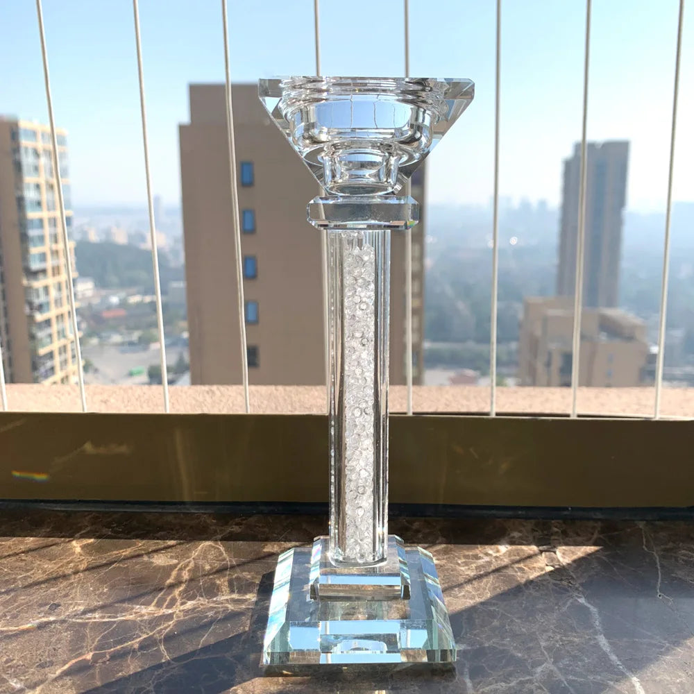 Clear glass candle holder on a marble surface with a cityscape in the background
