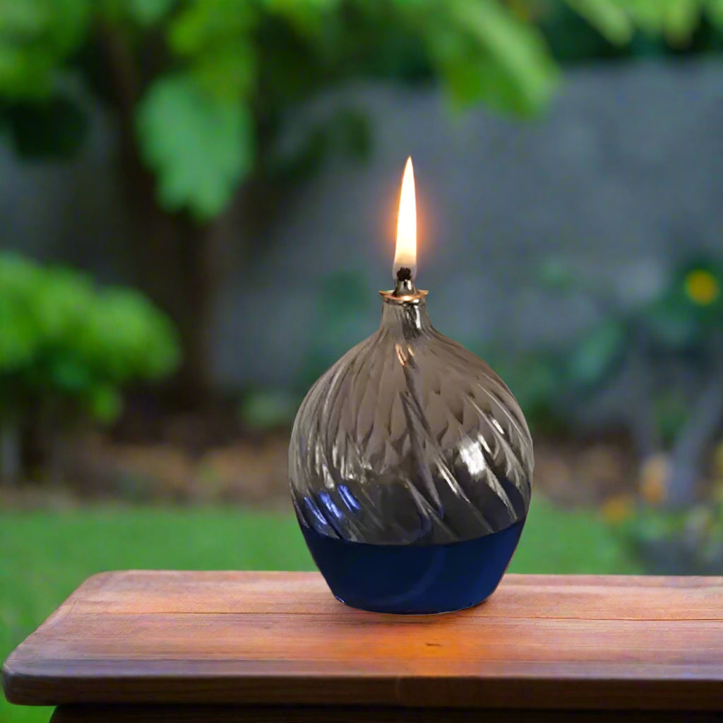 Decorative glass oil lamp with blue oil, on an outdoor table