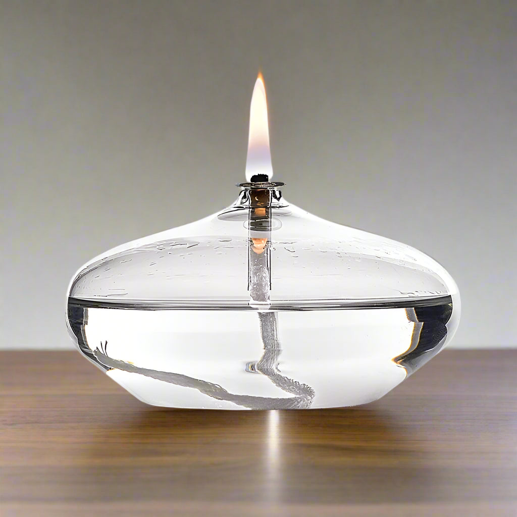 Clear glass oil lamp with a visible flame on a desktop