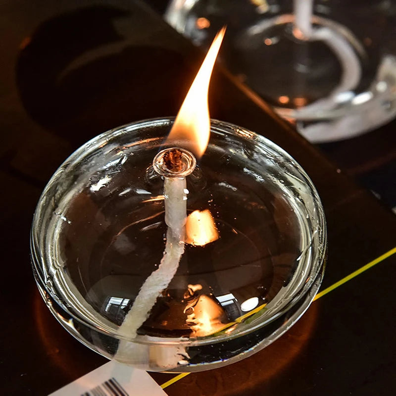 Candle in a glass jar with a lit wick on a dark background