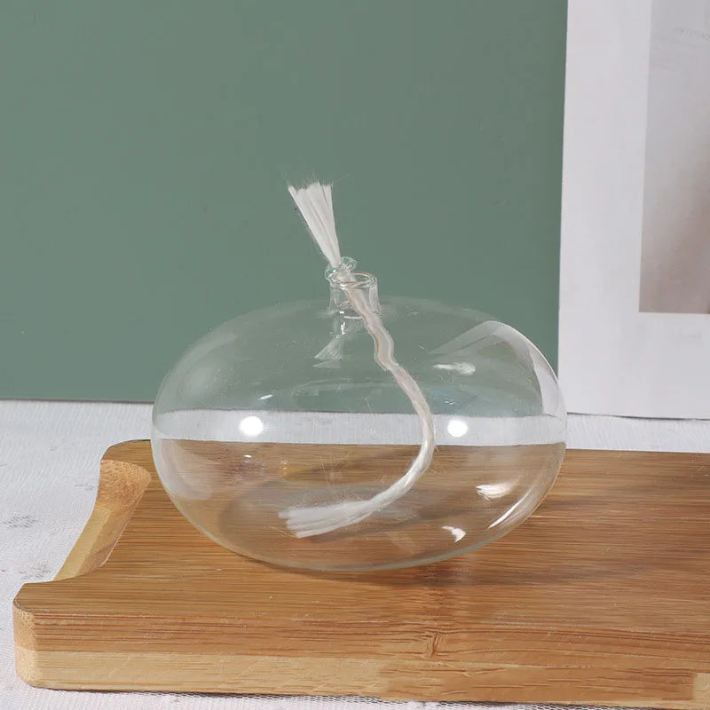 Clear glass orb with a string on a wooden surface against a green wall.