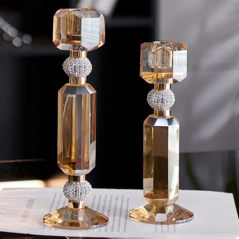 Two elegant crystal candlesticks with faceted amber-tinted glass and sparkling rhinestone accents, displayed on a white surface with a blurred background.