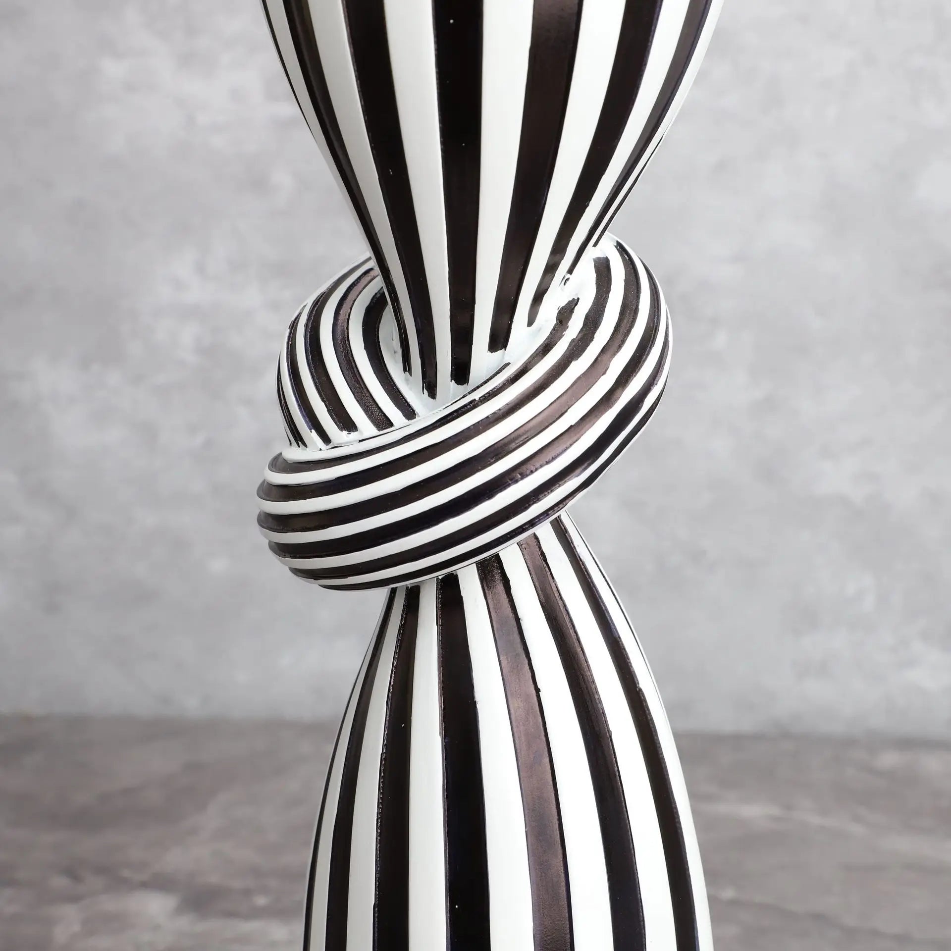 Black and white striped vase with a knot design on a gray background