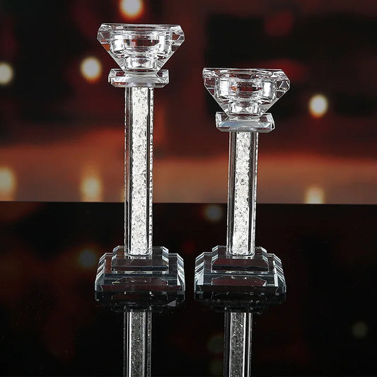 Two crystal candle holders on a reflective surface with a blurred background