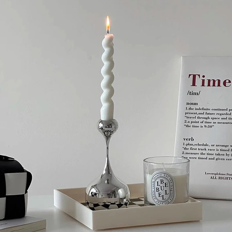 White candle in a silver holder on a white surface with a white box labeled 'Time' in the background.