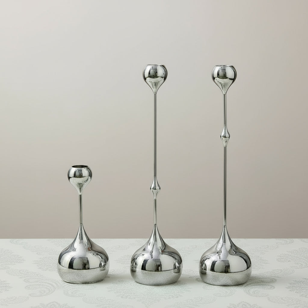 Set of three silver candle holders on a pastel background