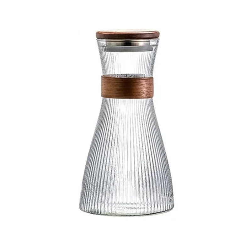 A clear ribbed glass carafe with a brown wooden lid and a matching brown band around the neck, shown on a plain white background.