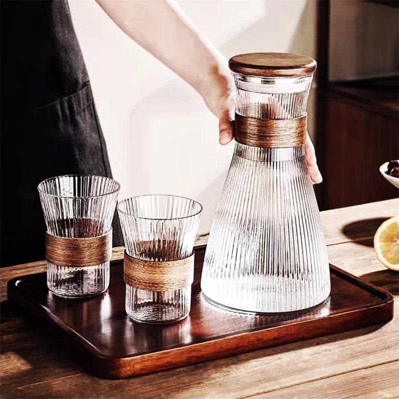 Ribbed glass carafe and tumblers with wooden bands on a wooden tray.