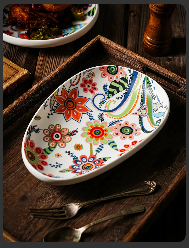 Colorful floral-patterned ceramic dish on a wooden surface with cutlery.