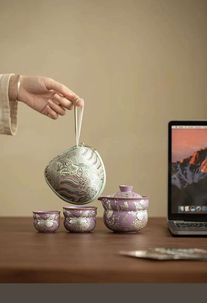 Tea set on a wooden table, with a hand holding the special carry bag.