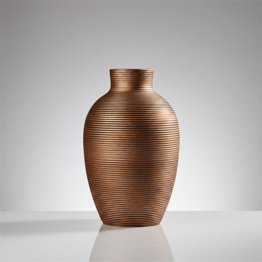 Bronze ribbed vase on a reflective surface, with a grey background 