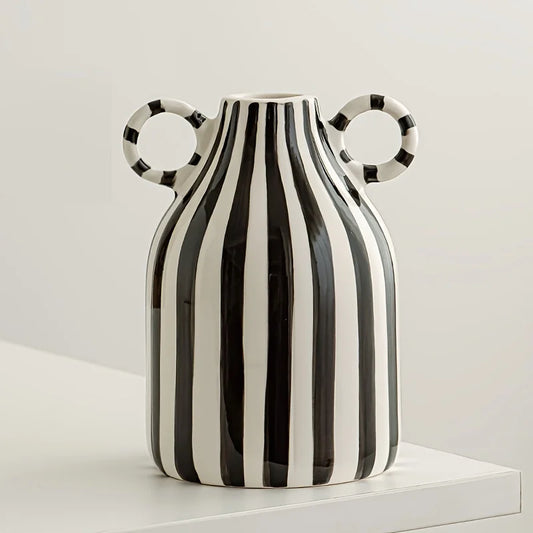 Black and white striped vase with circular handles on a white surface.