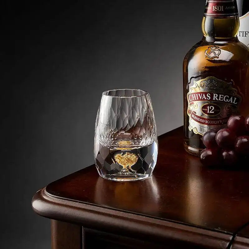 Chivas Regal 12 whisky bottle with a glass and grapes on a wooden table