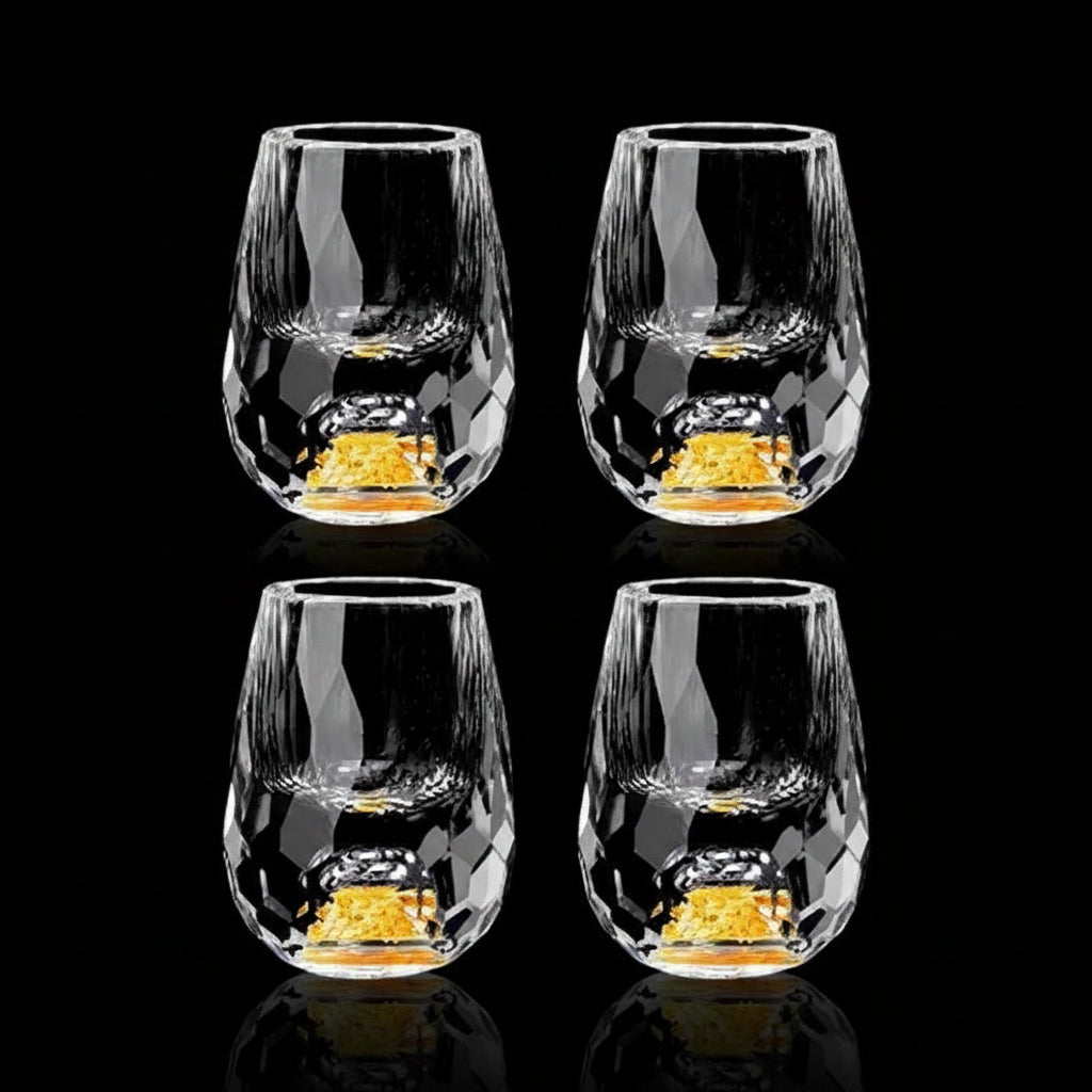 Set of four clear glass tumblers with gold interior on a black background