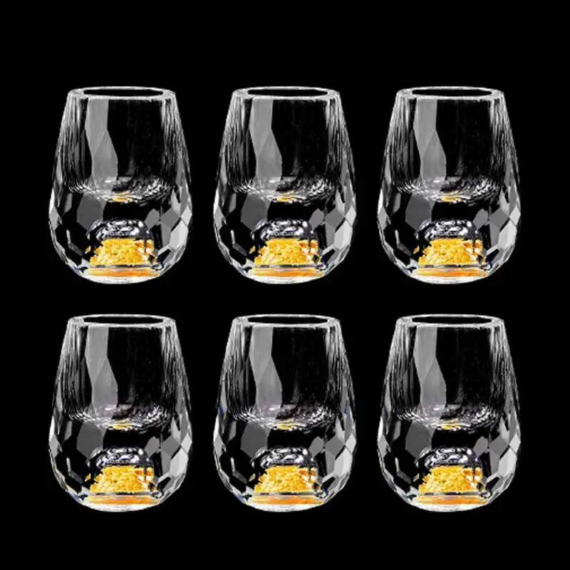 Set of six clear glass tumblers with gold interior on a black background