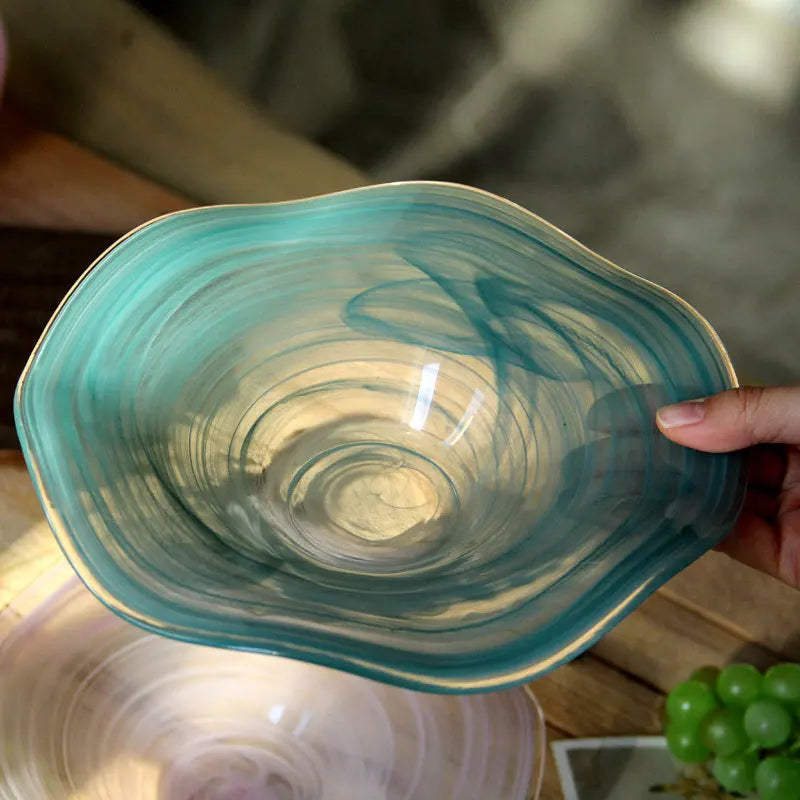 Hand holding a blue glass bowl with a swirling pattern