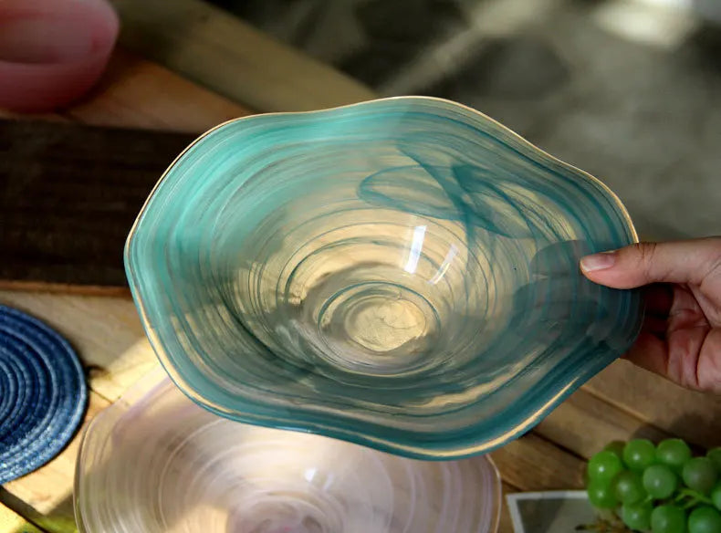 Hand holding a teal glass bowl with a blurred background