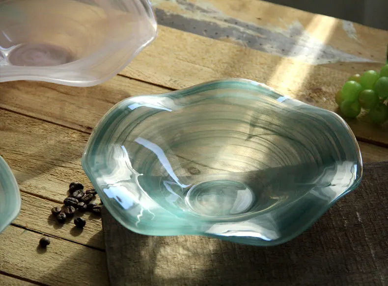 Glass bowl on a wooden surface with grapes and coffee beans.