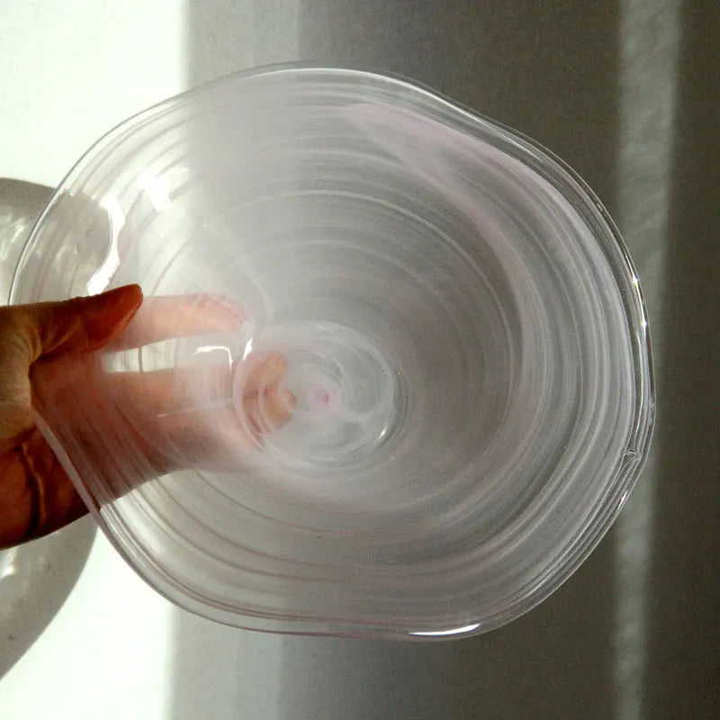 Transparent + white glass bowl held by a hand against a neutral background