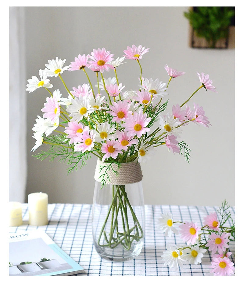 Bouquet of pink and white flowers in a clear vase on a table with a checkered tablecloth.