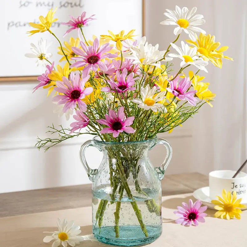 Clear glass pitcher filled with colorful flowers on a wooden surface.