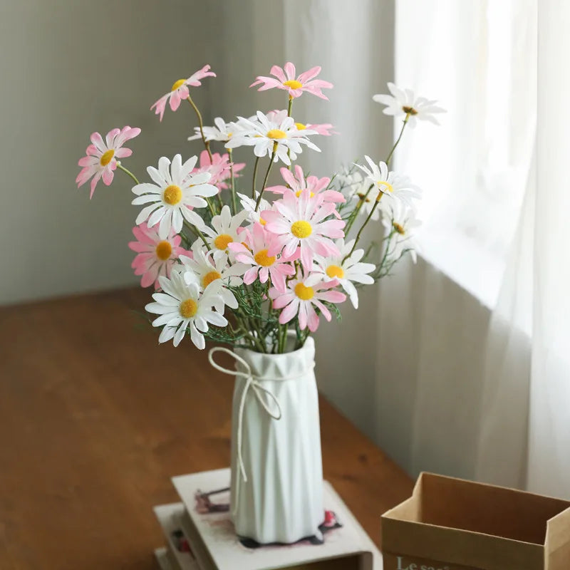 Bouquet of pink and white flowers in a white vase on a wooden surface.
