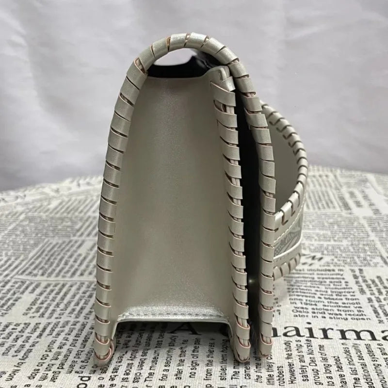 Metallic handbag with a textured handle on a newspaper background