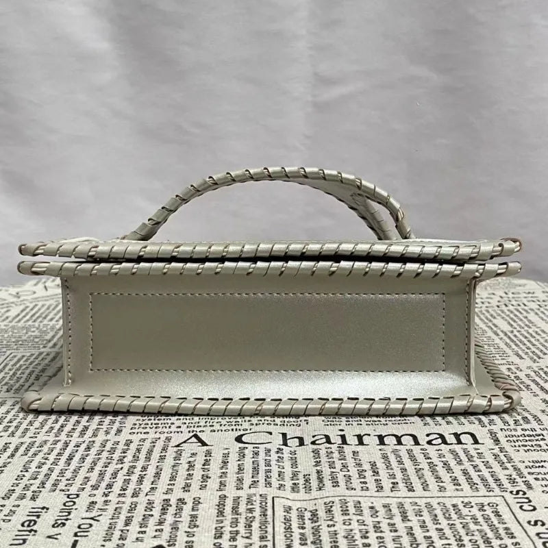 Silver handbag with woven handle on a newspaper background