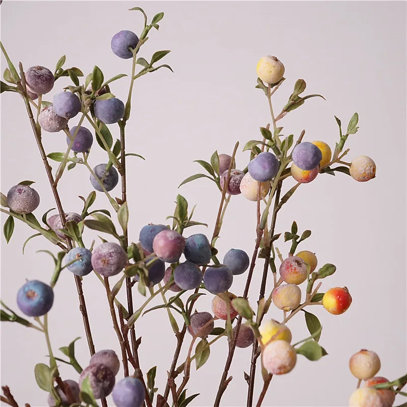 Artificial apple branches with purple, green, and red berries on a light gray background