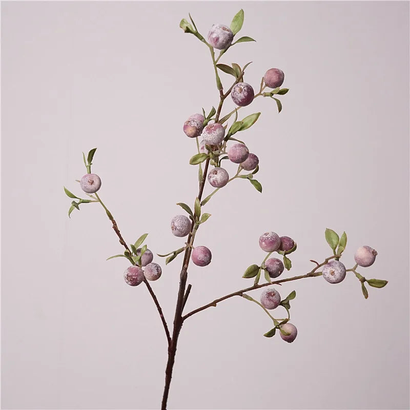 Artificial branch with green leaves on a light pink background