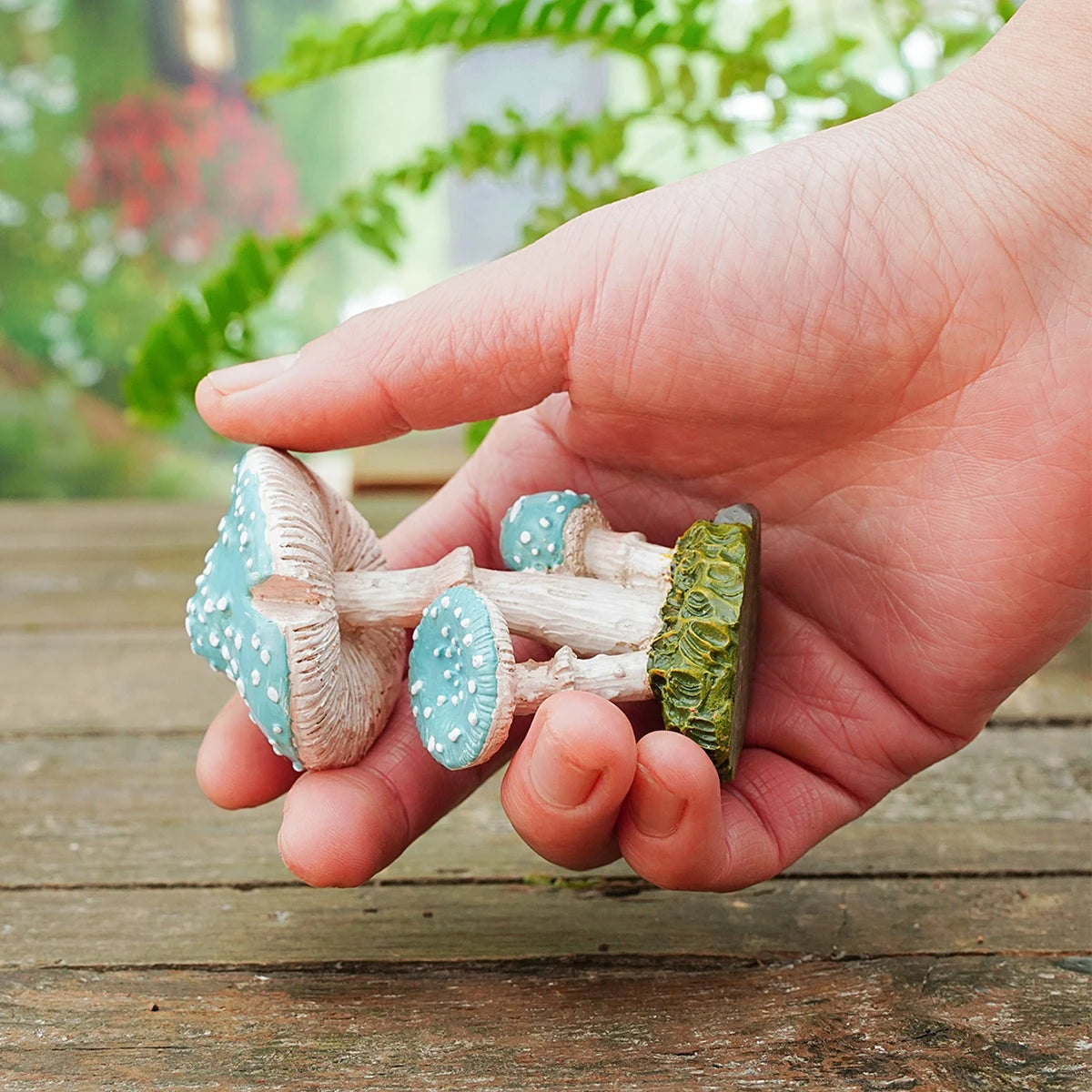 Hand holding decorative mushrooms with a blurred garden background