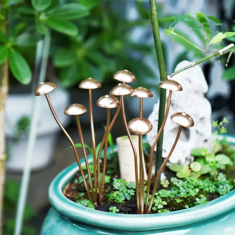 Decorative metal mushroom lights in a pot with greenery
