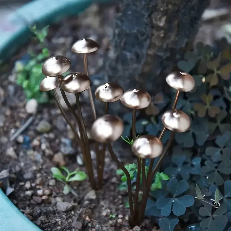 Metallic decorative mushrooms in a pot with plants