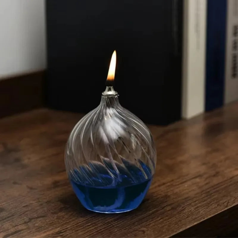Glass container with blue liquid and a lit candle on a wooden surface