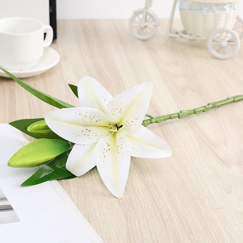White lily flower on a wooden surface with a cup and saucer in the background