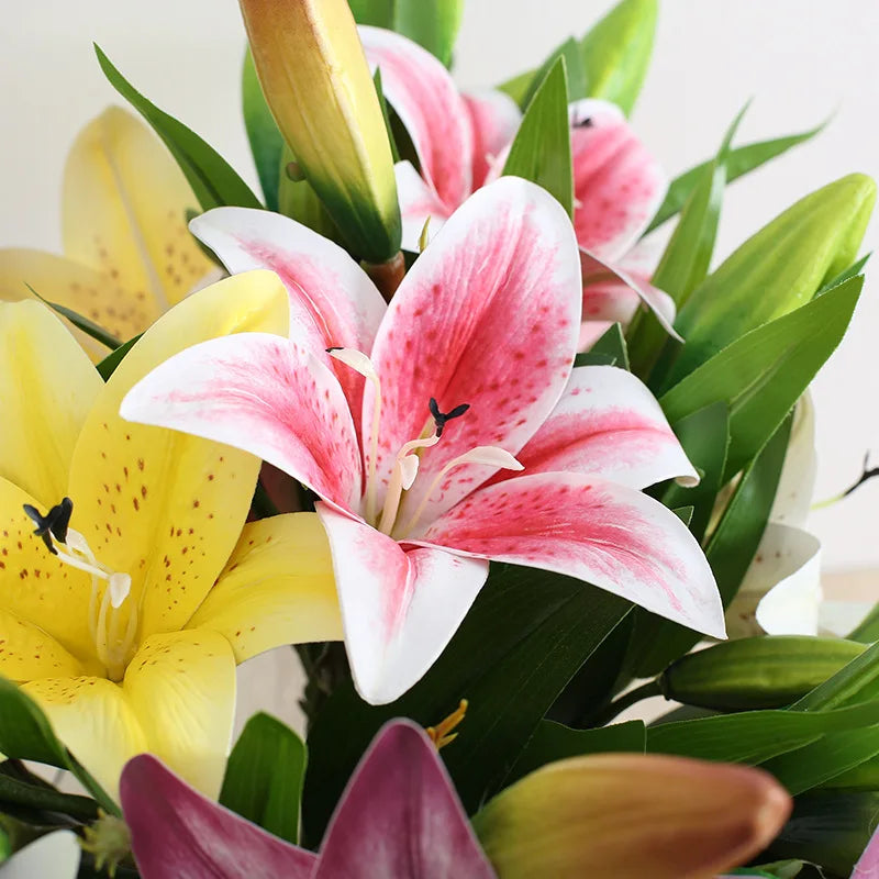 Bouquet of pink, yellow, and purple lilies with green leaves.