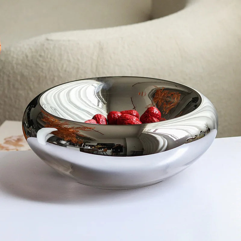 Silver mirror glass bowl with fruit, on a white surface
