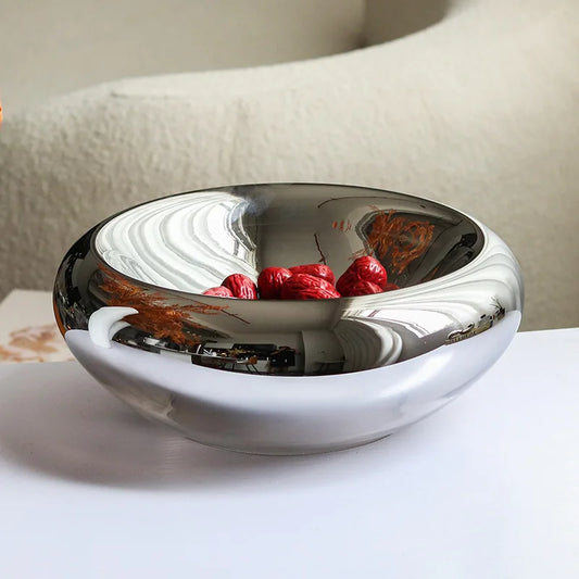 Silver mirror glass bowl with fruit, on a white surface
