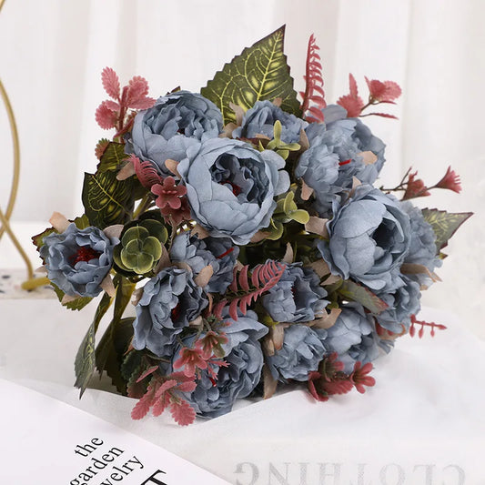 Bouquet of artificial flowers with blue peonies and green leaves on a white background