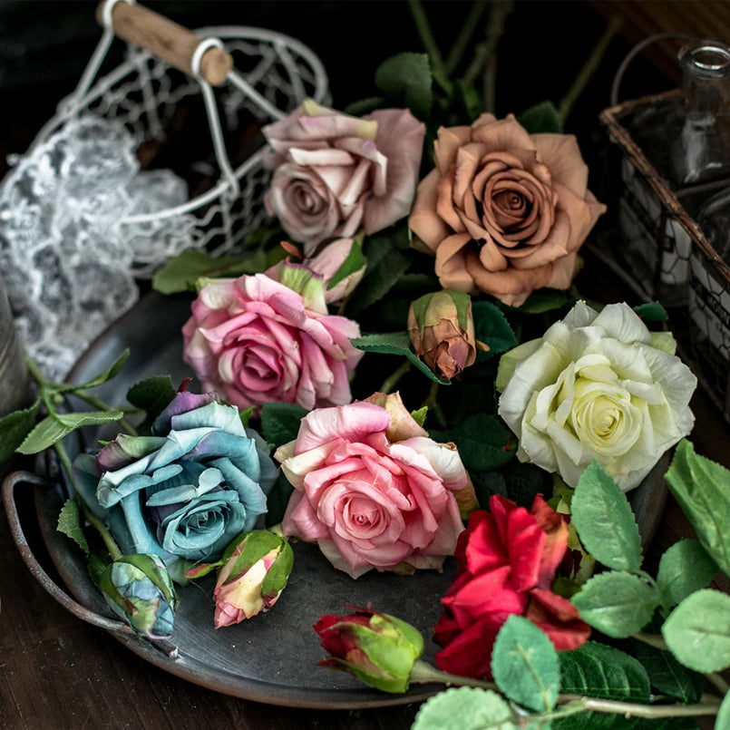 Colorful roses on a dark surface with a lace doily and bottle in the background