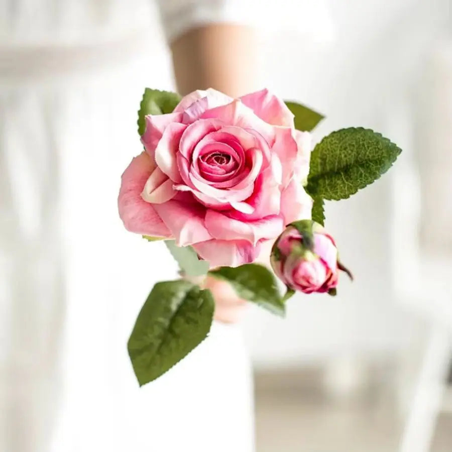 Close-up of a pink rose with green leaves on a blurred background