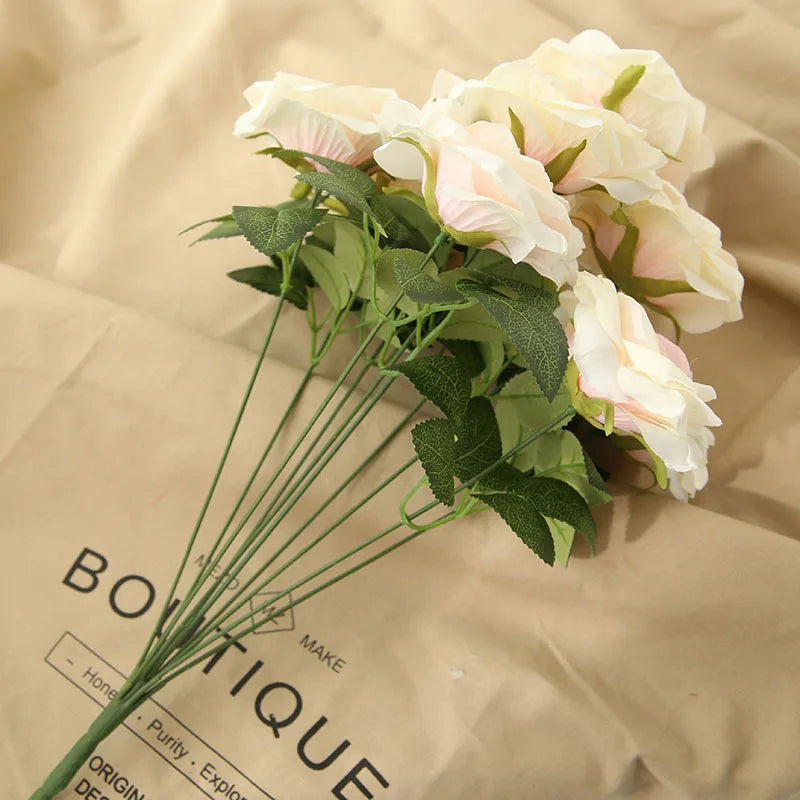 Bouquet of artificial flowers on a beige surface with 'Boutique' branding.