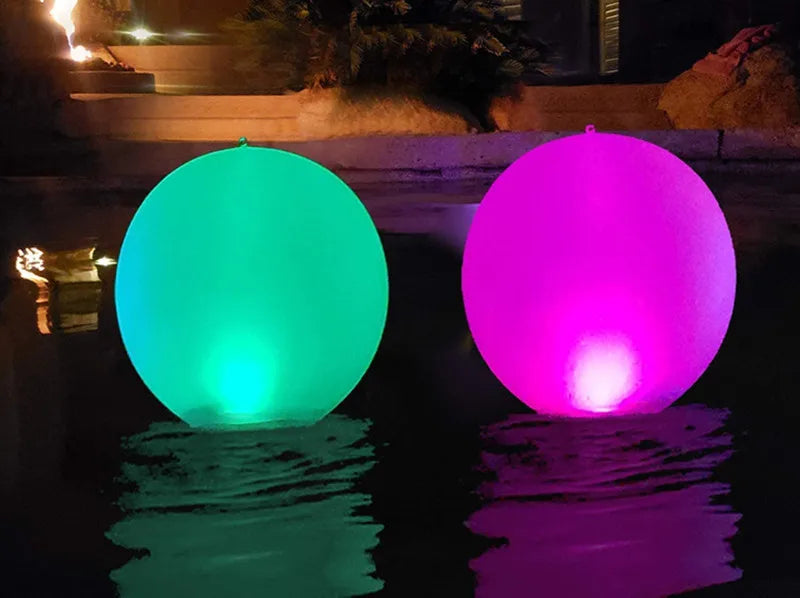 Two colorful LED balloons floating on water at night.