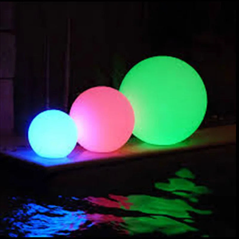 Three glowing balls in green, pink, and blue on a dark background.