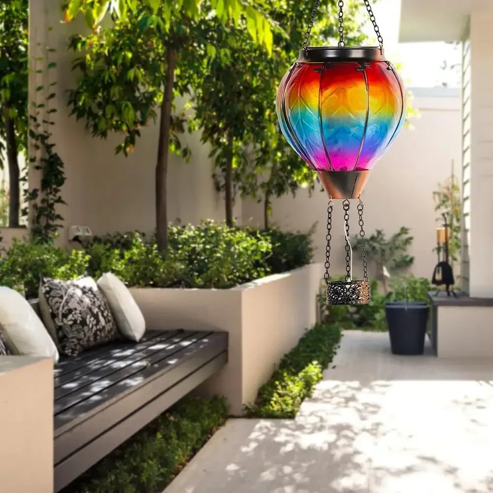 Colorful hanging lantern in a garden setting with a bench and plants.