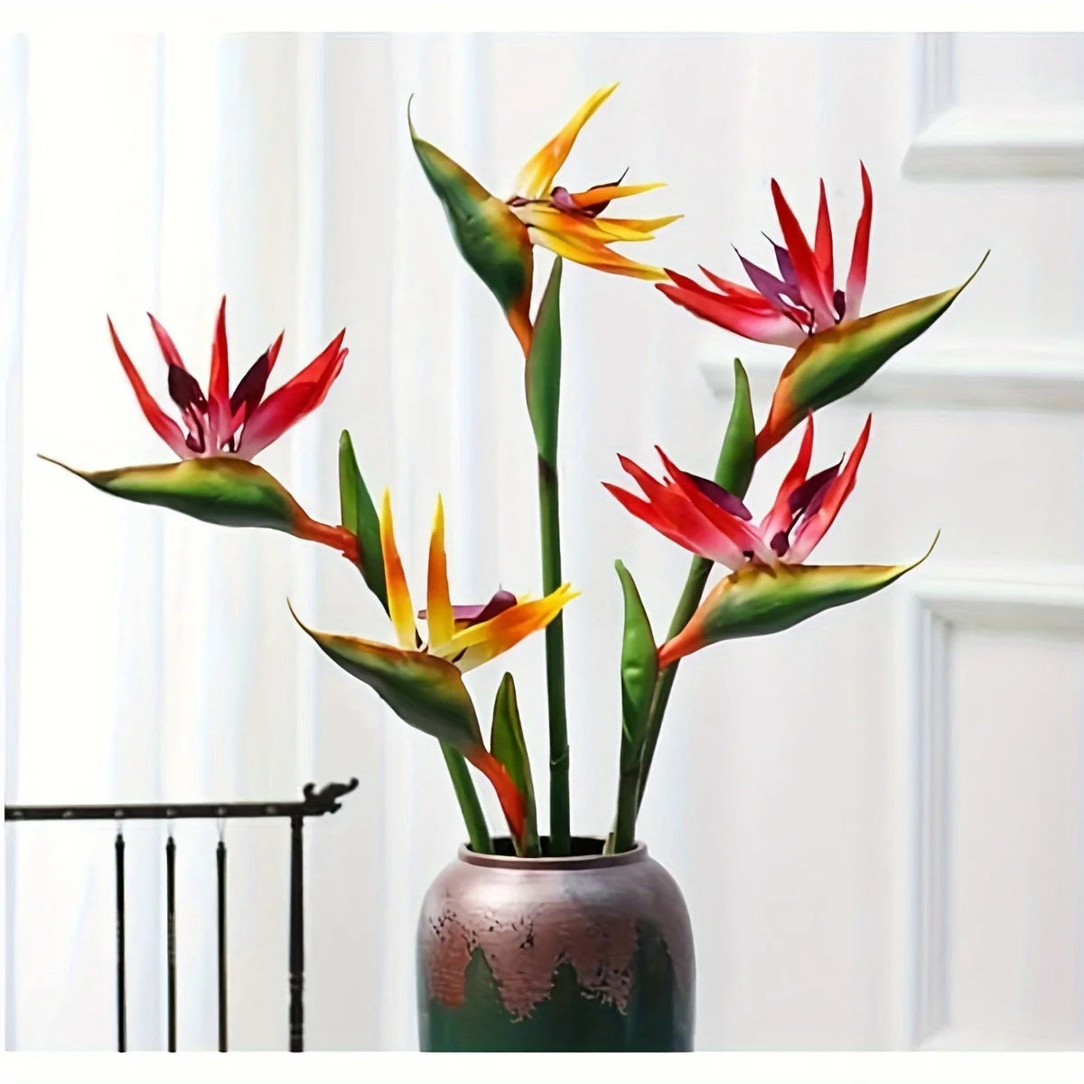 Artificial bird of paradise flowers in a vase against a white background