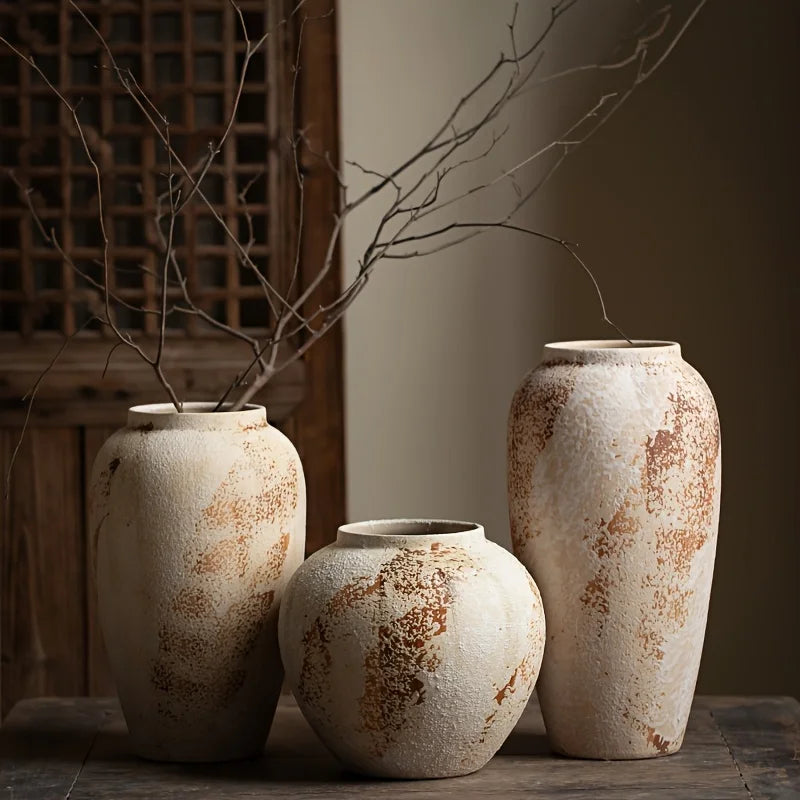 Three rustic ceramic vases with a textured surface on a wooden surface.