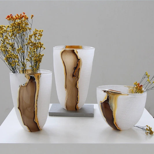 Three modern agate-patterned ceramic vases in white and brown tones, styled with dried yellow flowers on a white table against a light gray background.